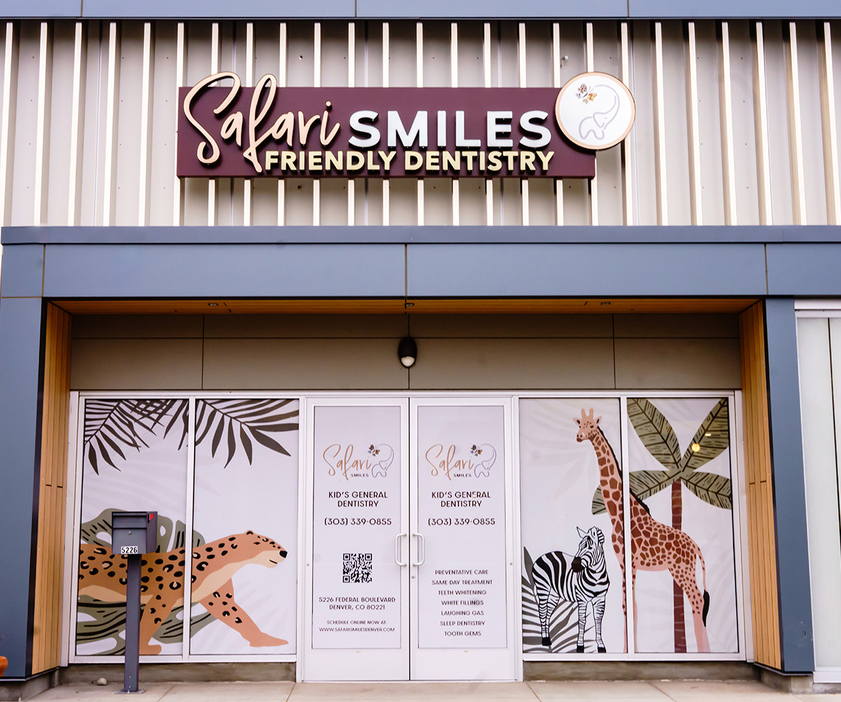 The image shows a sign for Sali Smiles Friendly Dentistry with a colorful mural depicting animals and plants behind it.